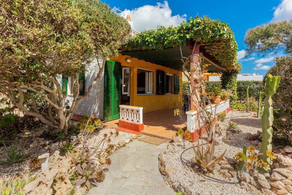 a small yellow house with a green door at Buena Ventura Villa in Cala en Bosc