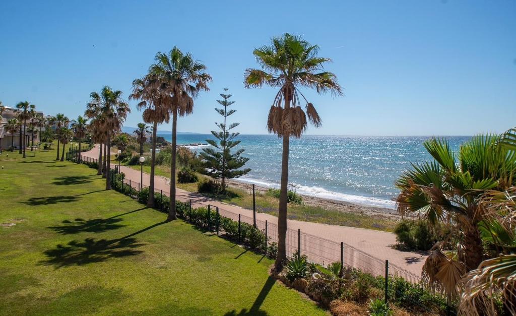 a walkway next to the beach with palm trees at Fantastic beachfront apartment in Estepona