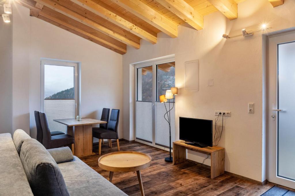a living room with a couch and a tv and a table at Ferienwohnung Grubig in Ehrwald