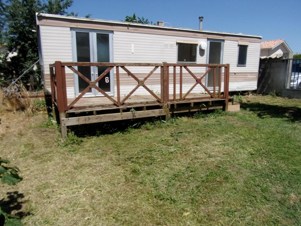 a mobile home with a wooden gate in a yard at Mobil'Home du Sancillon in Charentay