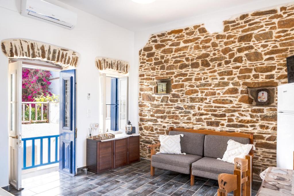 a living room with a couch and a brick wall at Olga's House Kythnos in Kithnos