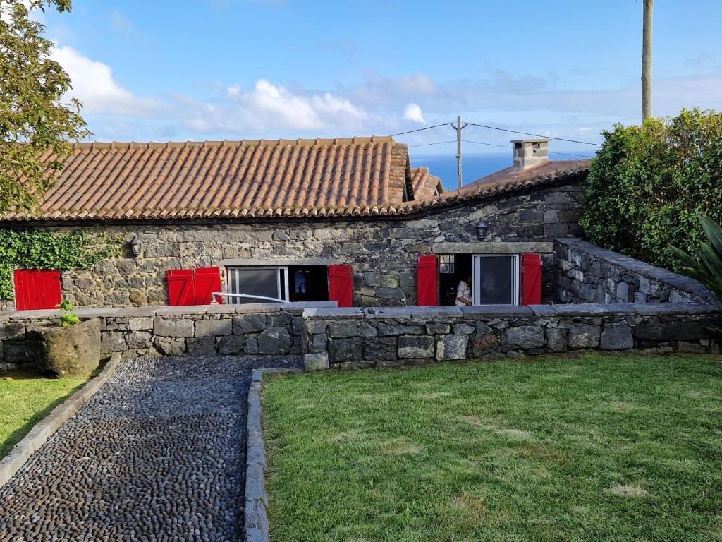 a stone house with red doors and a yard at Ponta da Amora in Ponta Garça
