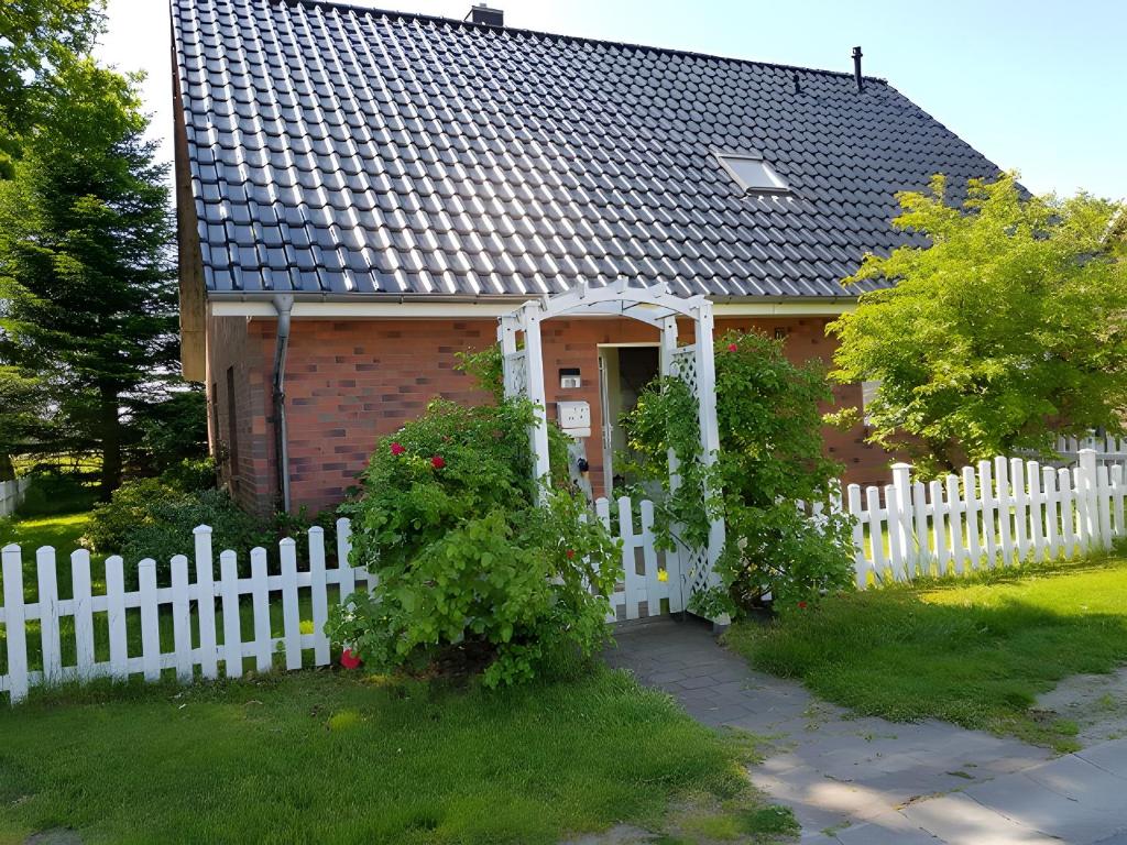 a white fence in front of a house at Ferienwohnung Abendsonne in Lehe