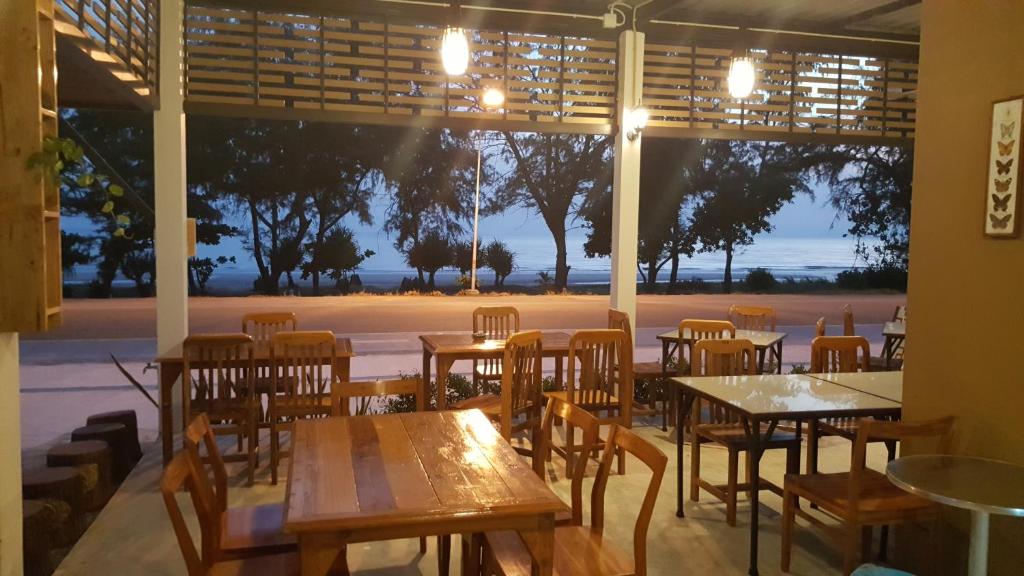 a restaurant with tables and chairs and a large window at Yellow House Rayong in Ban Phe