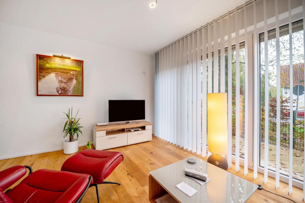 a living room with red chairs and a television at Ferienwohnung an der Gustavsburg in Homburg
