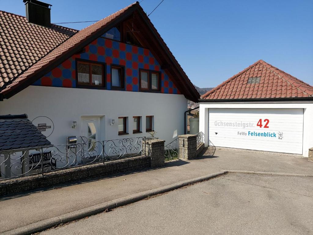 a white house with a red and white garage at Ferienwohnung Felsenblick in Albstadt