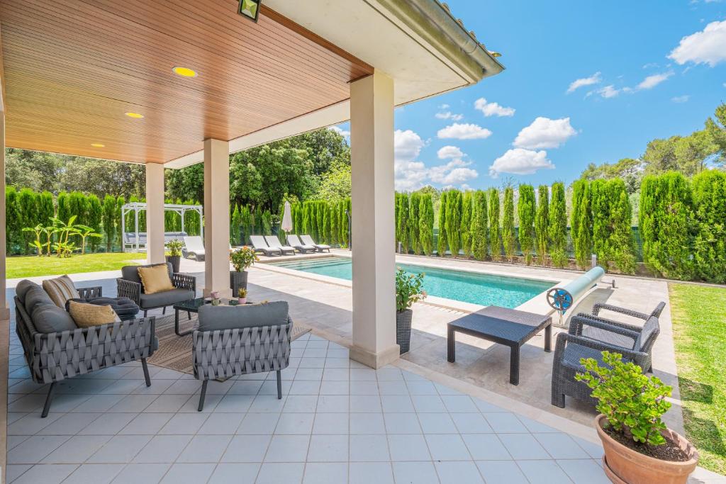 an outdoor patio with chairs and a swimming pool at Villa Sa Olivera in Crestatx