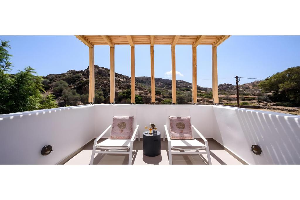 a balcony with two chairs and a table on it at Echinousa Kimolos Maisonette no1 in Kimolos