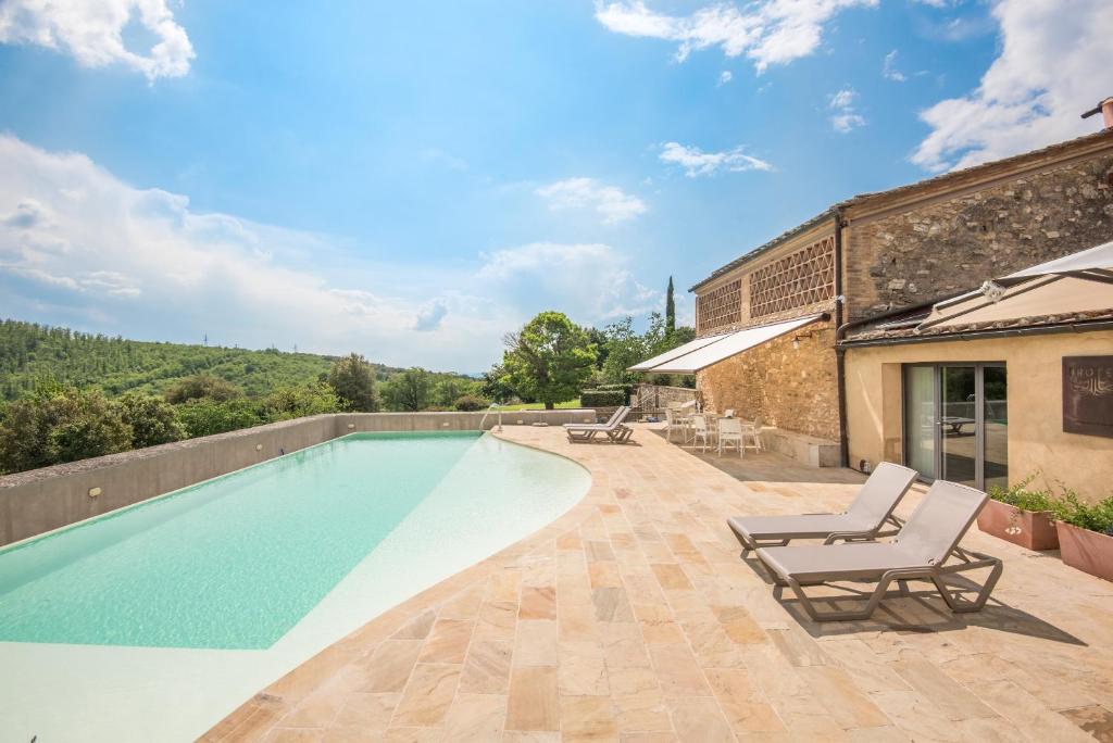 a swimming pool with two lounge chairs next to a building at Brotes Appartamento Mandorlo in Sovicille