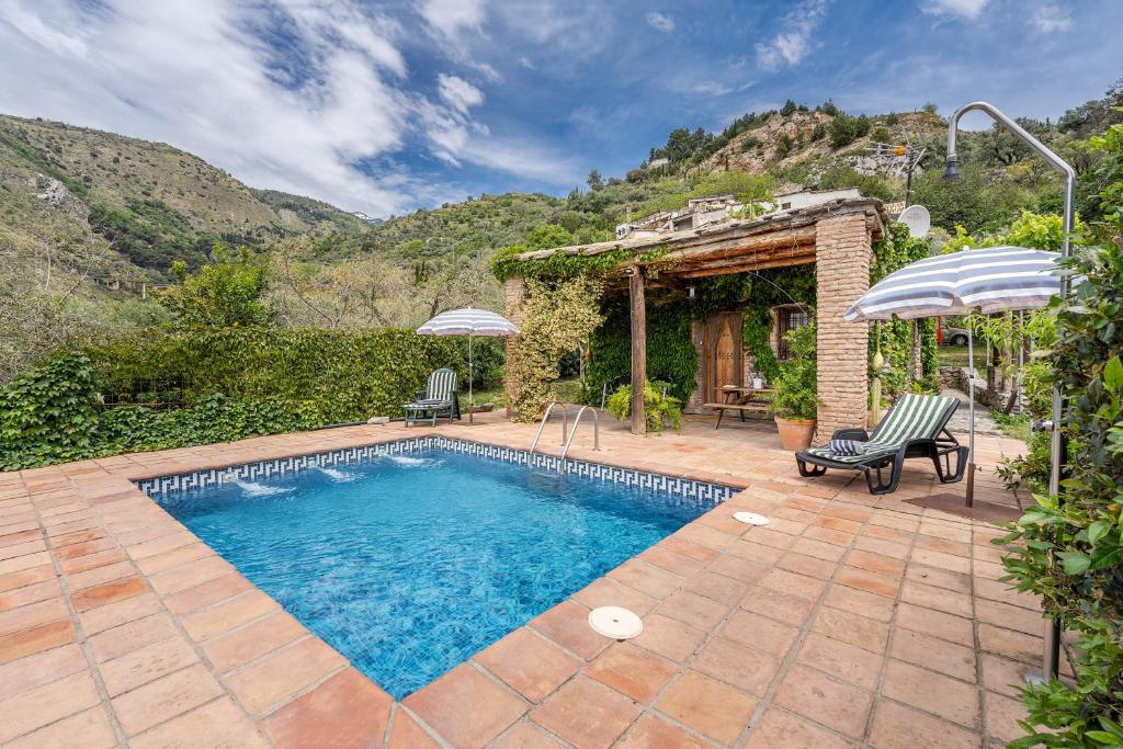 a swimming pool with two chairs and a house at La Terrera in Órgiva