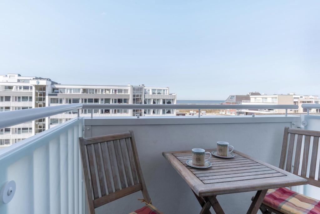 a wooden table on a balcony with two cups of coffee at Sylter Residenz Westerland in Westerland