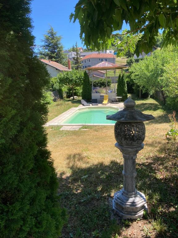 a stone birdbath sitting in the grass near a pool at Le Kiosque de Compostelle in Espaly-Saint-Marcel