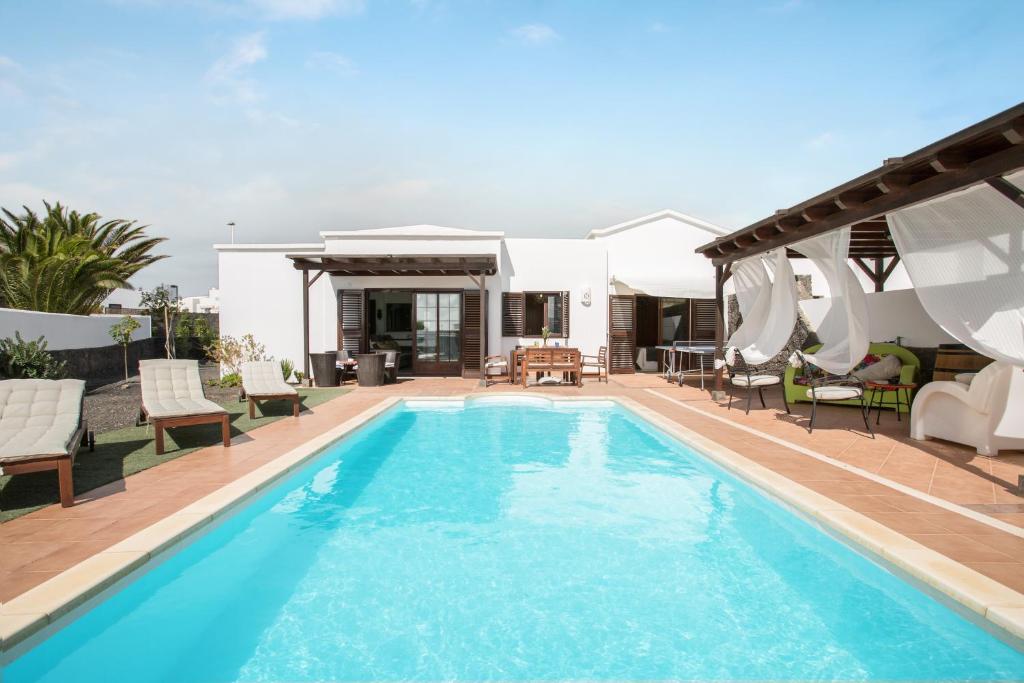 a swimming pool with chairs and a house at Villa Kodotoma in Yaiza