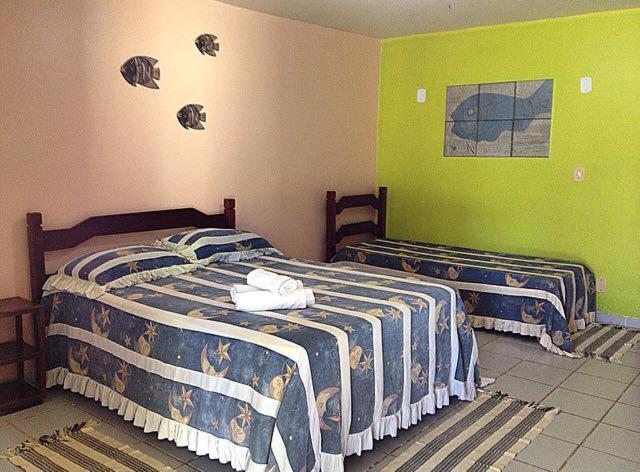 two beds in a room with green walls at Pousada Laguna Mar in Marechal Deodoro