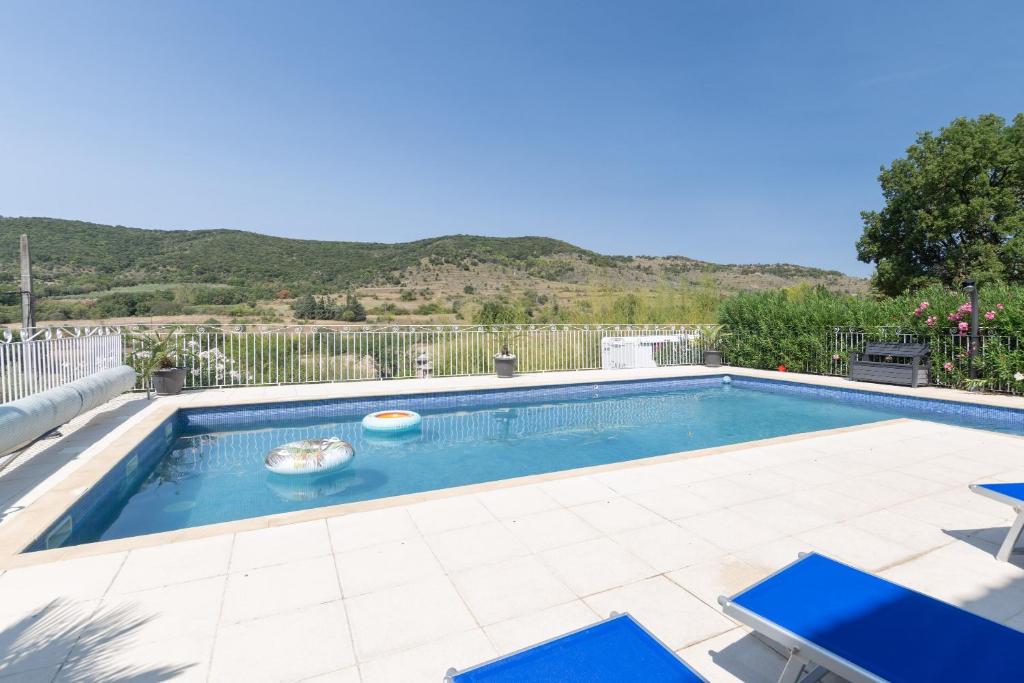 a swimming pool with two blue chairs next to at Appartement N°3 - Piscine Partagée in Lagorce