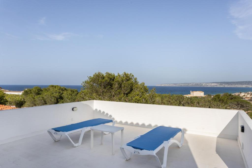 a patio with two blue chairs on a white wall at Ses Roques Casa del Sol in Illes Balears