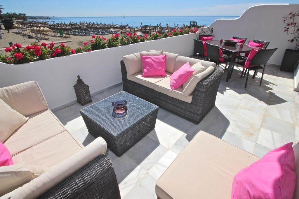 a patio with two couches and a table with pink pillows at Deluxe Apartment on the Beach in Marbella