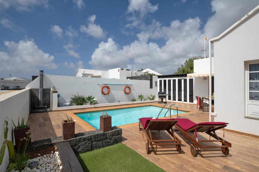 a backyard with a swimming pool and two chairs at Villa Calima Deluxe con Piscina in Tías