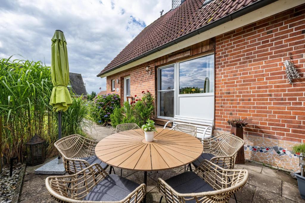 a wooden table with chairs and an umbrella on a patio at Ferienwohnung Meeresbrise in Grömitz
