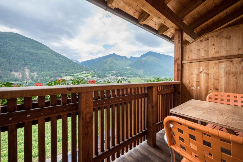 a wooden balcony with a table and chairs and mountains at Kreuzhof links in Novacella