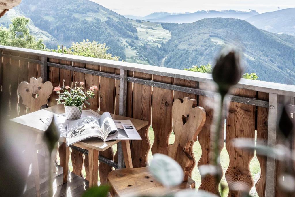 a table with a book on a balcony with mountains at Oberhof Apt Lärchenwald in Vallarga