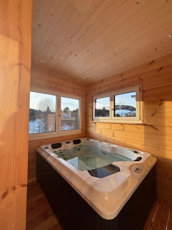 a large bath tub in a wooden room with windows at Mettmapark - Chalet 2 in Grafenhausen