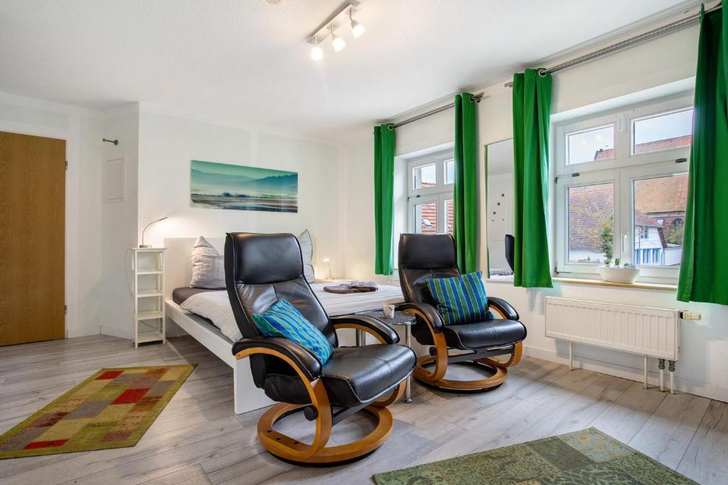 a bedroom with two chairs and a bed with green curtains at Bäckerhus - Ferienwohnung 5 in Wiek auf Rügen