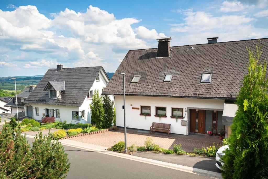 two white houses with a bench on a street at Am Pön - Ferienwohnungen in Medebach