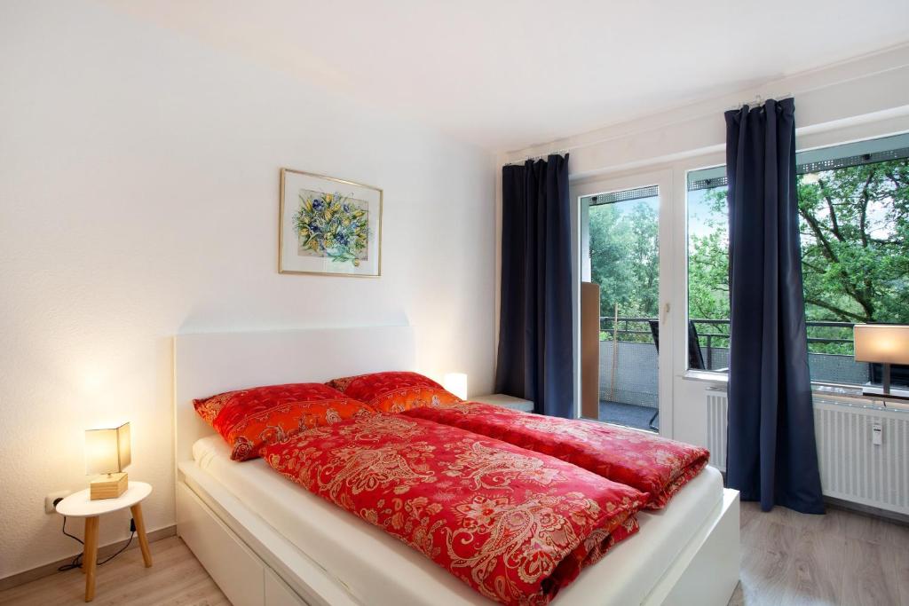 a bedroom with a bed with red sheets and a window at Ferienwohnung Rübezahl in Brilon