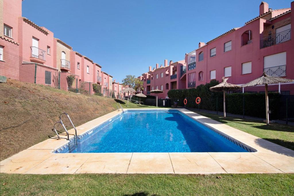 a swimming pool in a yard next to some buildings at Duplex Luminoso Campo de Golf in Islantilla