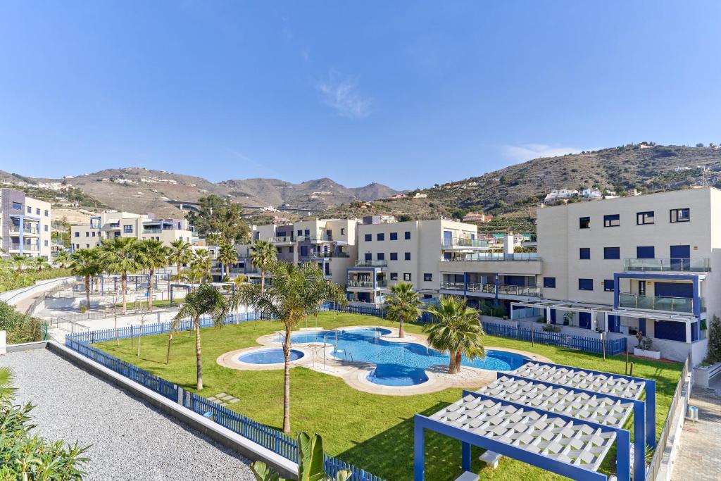an aerial view of a resort with two pools and palm trees at Apartamento Playa Cabria in Almuñécar