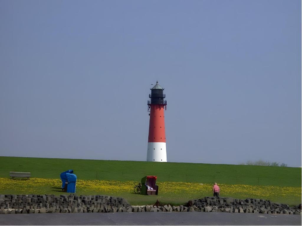 a red and white lighthouse sitting on top of a field at Fischerhus Anne Jensen in Pellworm
