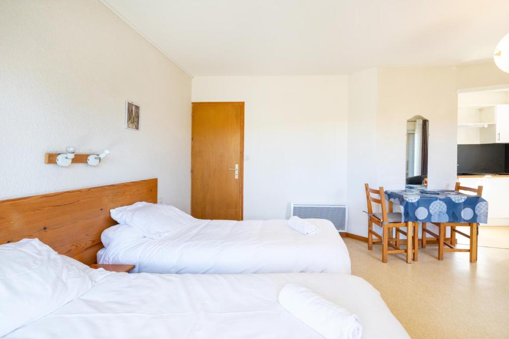 a hotel room with two beds and a table at Les Mimosas - Appartement 05 in Cazaubon