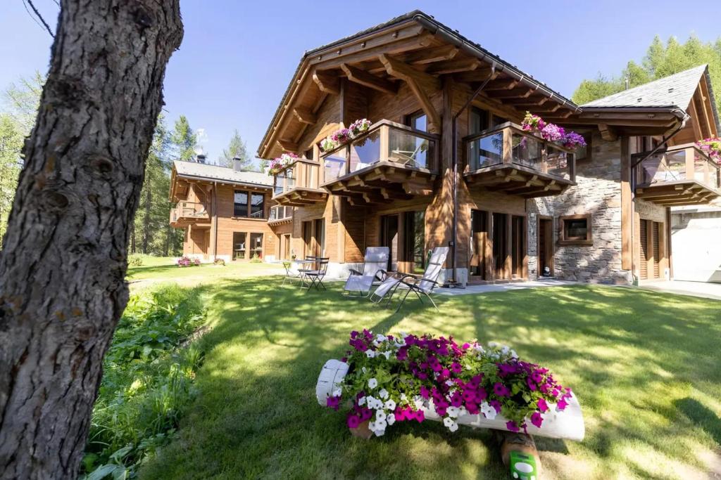 a log house with flowers in the yard at Chalet Imbosc'chè 5 rooms Bnb in Livigno