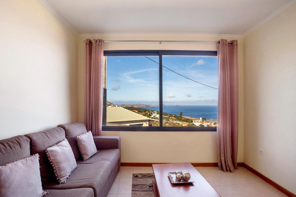 a living room with a couch and a large window at Casa da Bemposta in Machico