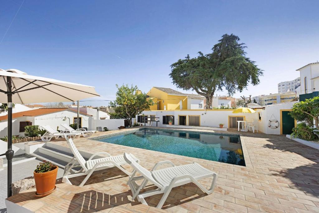 a swimming pool with two white chairs and an umbrella at A Cerca - A in Lagos