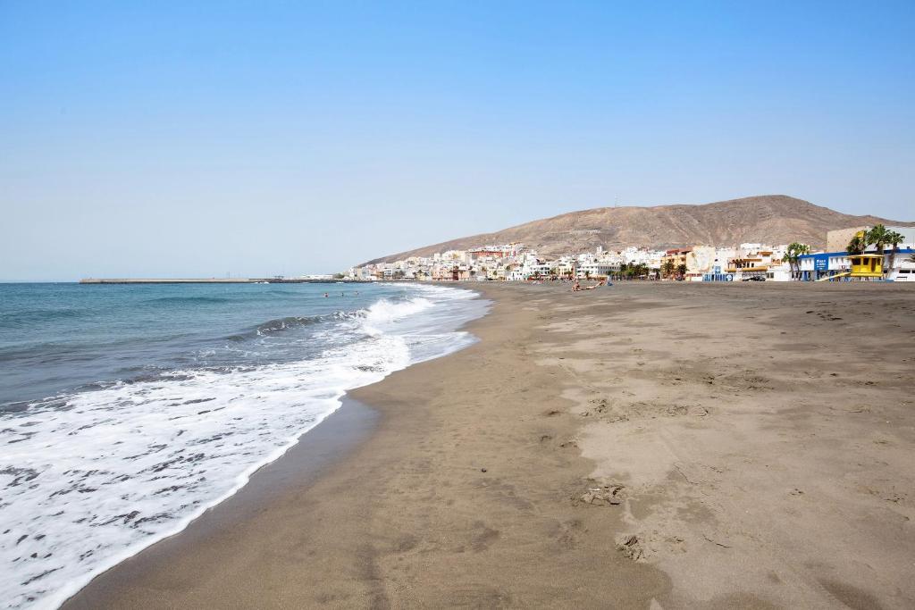 a beach with the ocean and buildings in the background at Casa Relax in Gran Tarajal