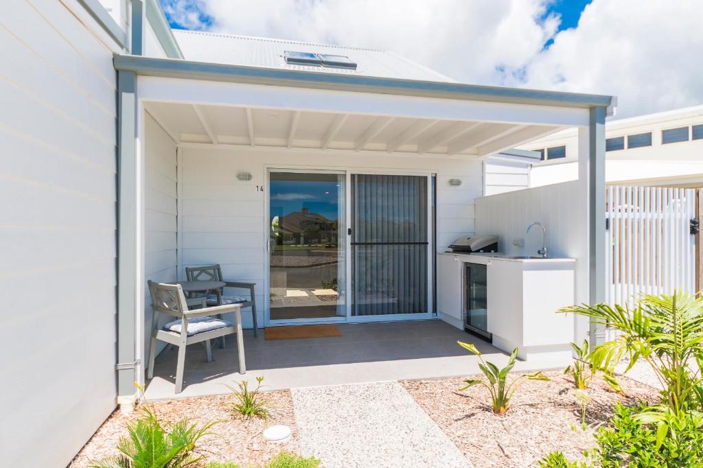 a white house with a patio with a table and a chair at Marina 14 Harrington in Manning Point