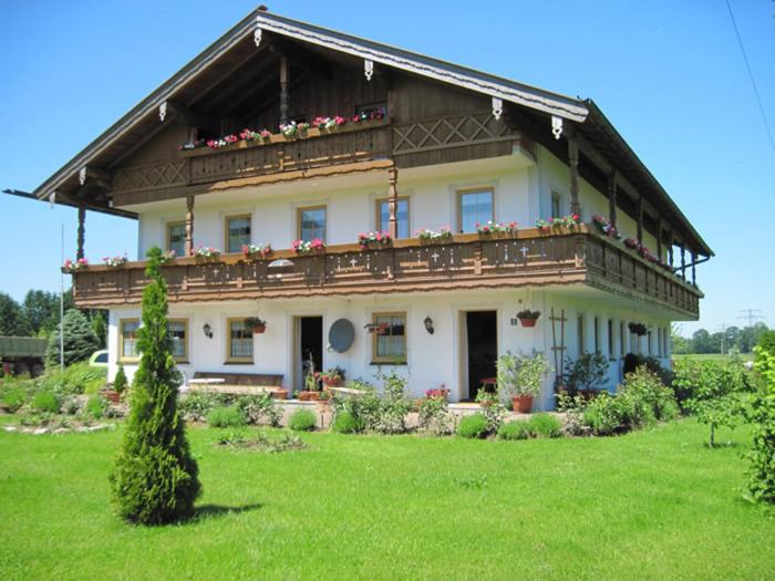 een groot huis met een balkon op een groen veld bij Schwaigerhof in Grassau