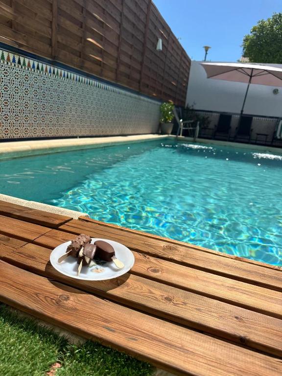 a plate with a piece of cake on a plate next to a swimming pool at Villa Gení in La Victoria