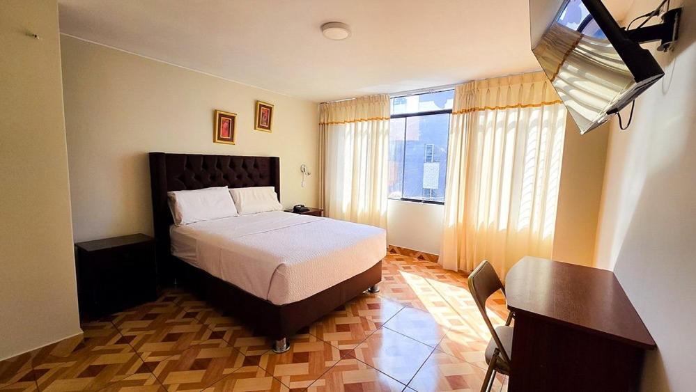 a bedroom with a bed and a desk and a window at Hotel Palmeras Tacna in Tacna