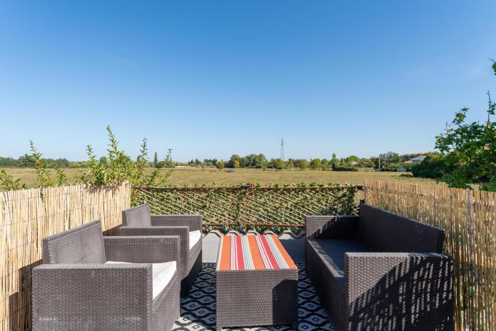 a row of wicker chairs in front of a fence at Appart Aux portes de la Camargue in Manduel