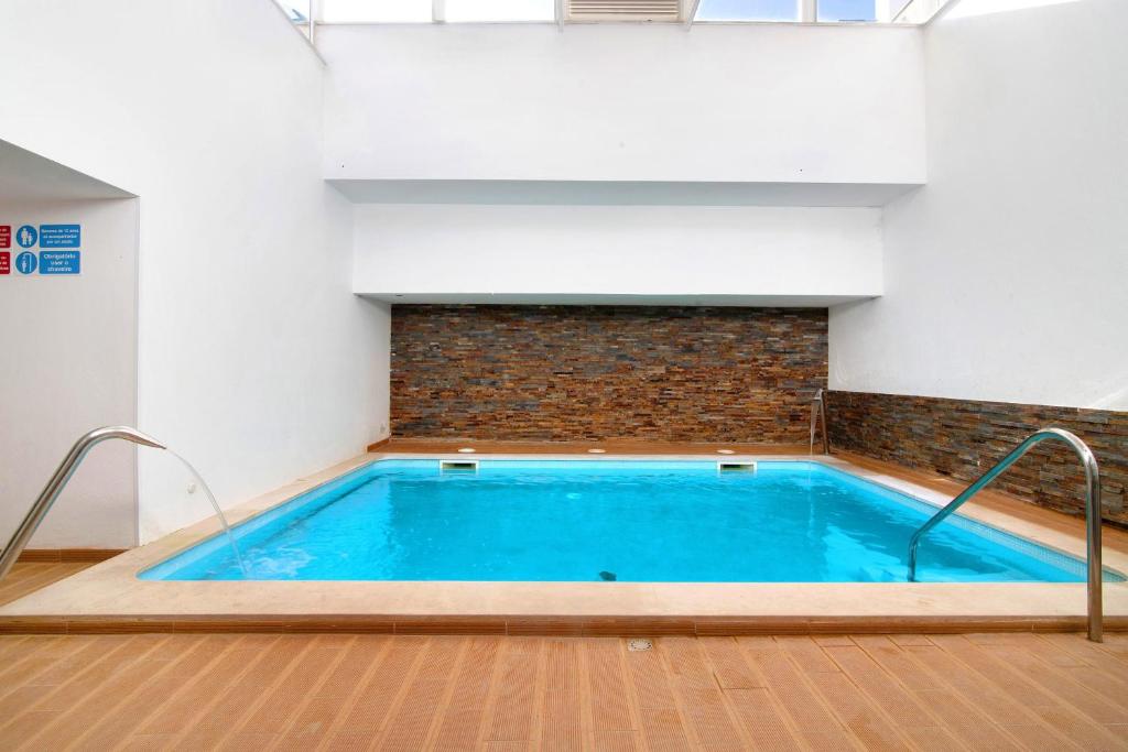 a large swimming pool in a room with a brick wall at Apartamento Maré Cheia Sl40 in Santa Luzia