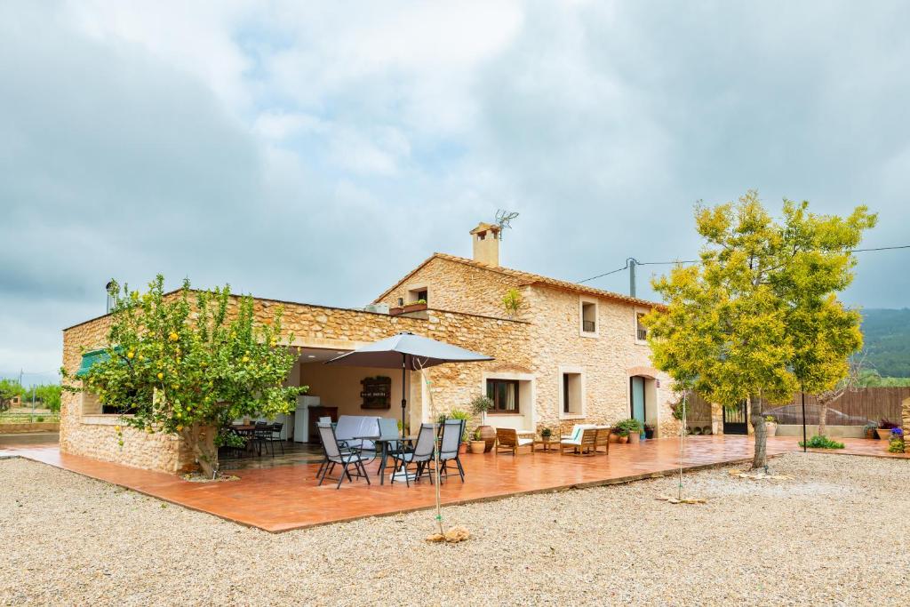 a stone house with a patio and table and chairs at Mas de Morera in Vall dʼAlba