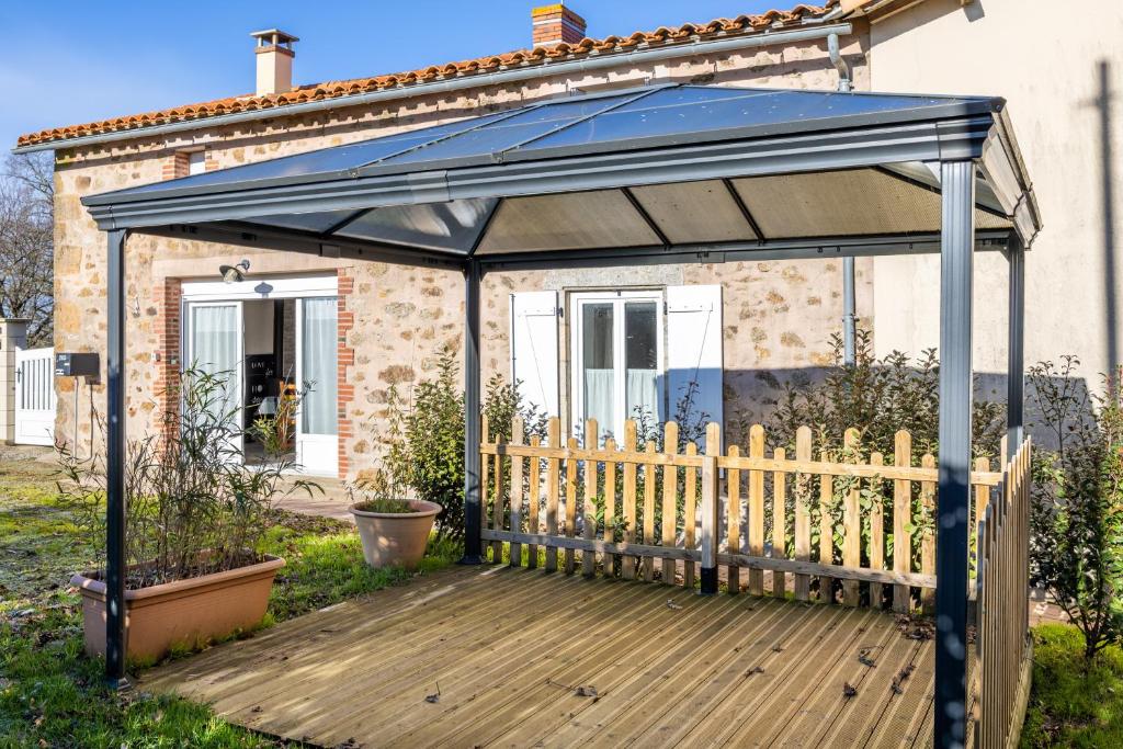 a gazebo with a wooden deck in front of a house at Gite Augustine Aux Charmes D'antan in Sevremont