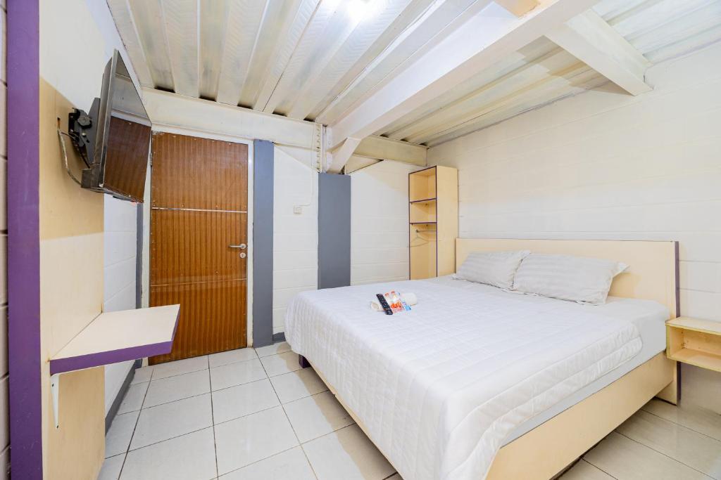 a small bedroom with a bed and a tv at Simple Hotel Bogor RedPartner in Bogor