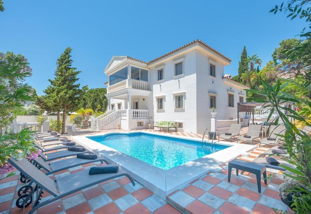 a villa with a swimming pool and lounge chairs at Villa Domus Vesta in Marbella