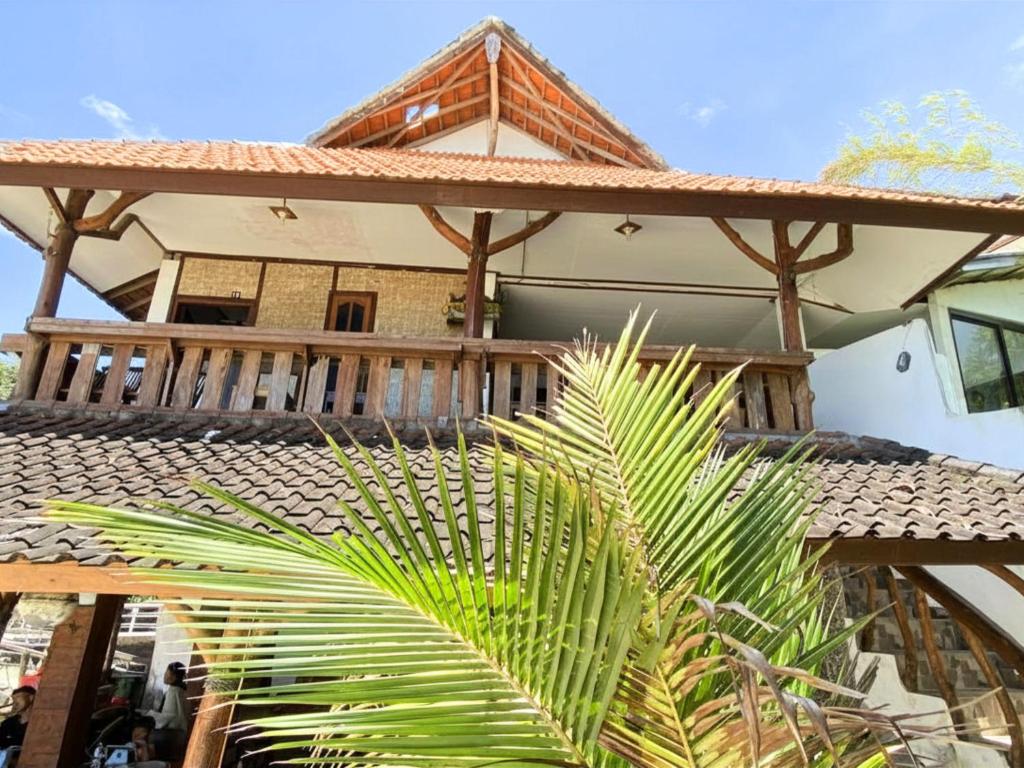 a house with a wooden deck and a palm tree at Santai Surf Lodge-Balangan in Uluwatu