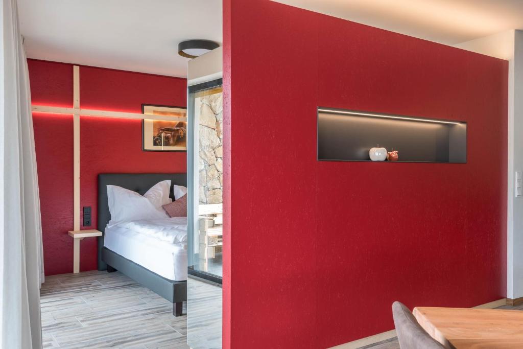 a bedroom with a red wall with a bed at Aumia Apartment Rubin in Völs am Schlern