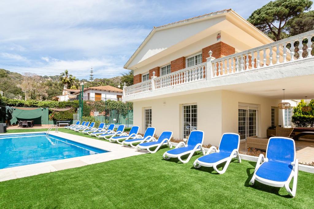 a villa with a swimming pool and blue chairs at Ainara Luxury in Lloret de Mar
